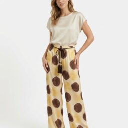 Femeie îmbrăcată cu un top deschis și pantaloni larga cu buline